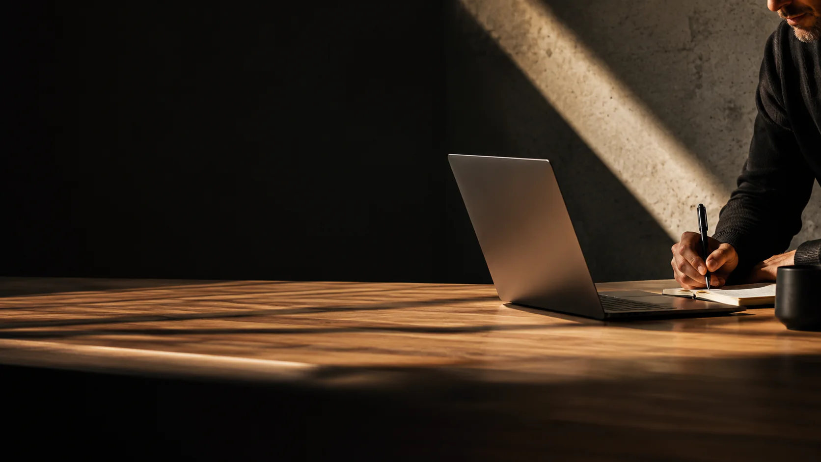 Szakember laptop mellett jegyzetel egy sötét munkatérben